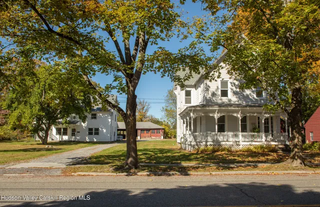 a front view of a house with a large tree