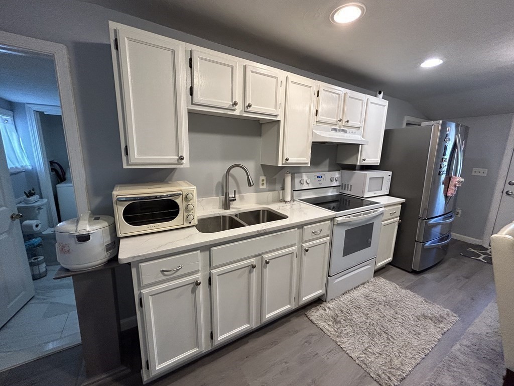 222 Gore Road Webster, MA 01570 - Photo 16 of 32 a kitchen with stainless steel appliances a sink a stove a refrigerator cabinets and a window