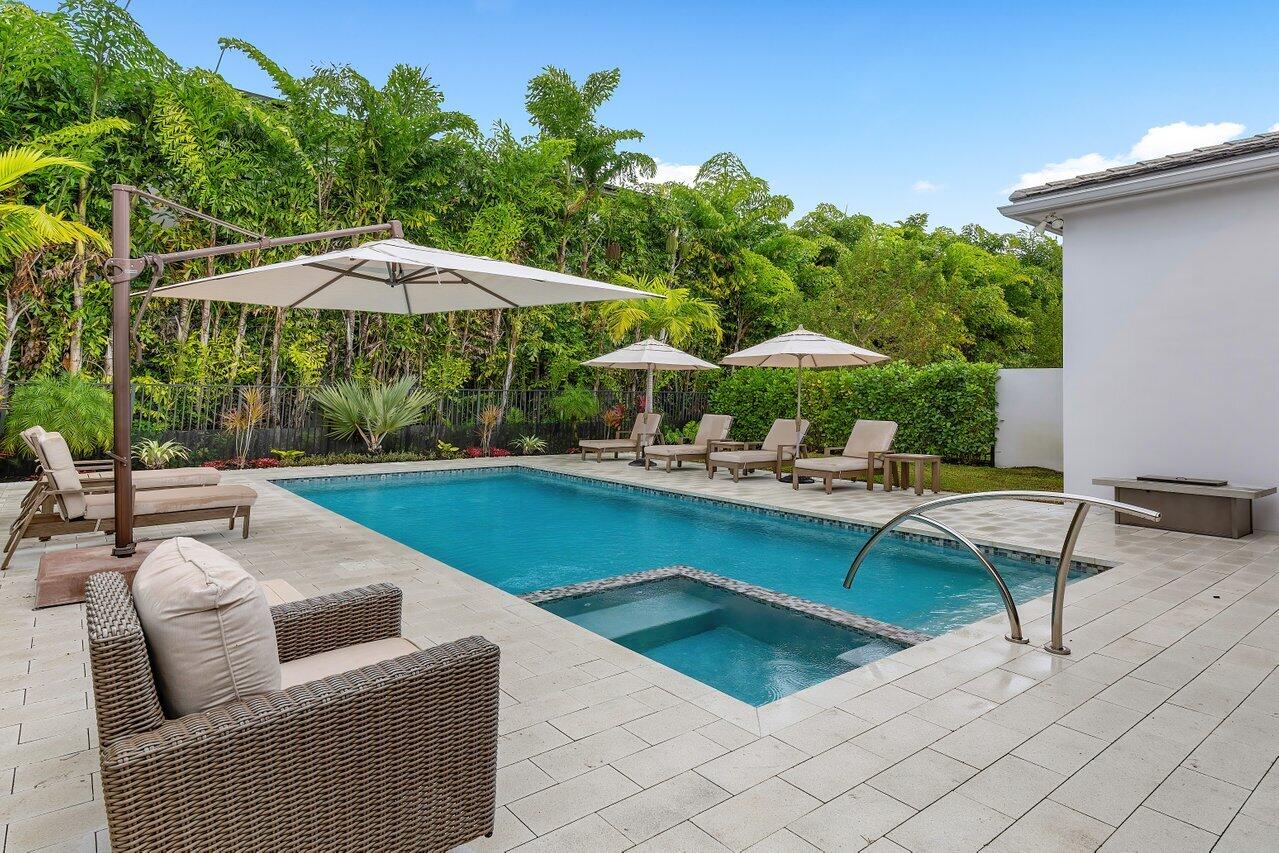9109 Fiano Place Boca Raton, FL 33496 - Photo 20 of 24 a backyard of a house with table and chairs under an umbrella