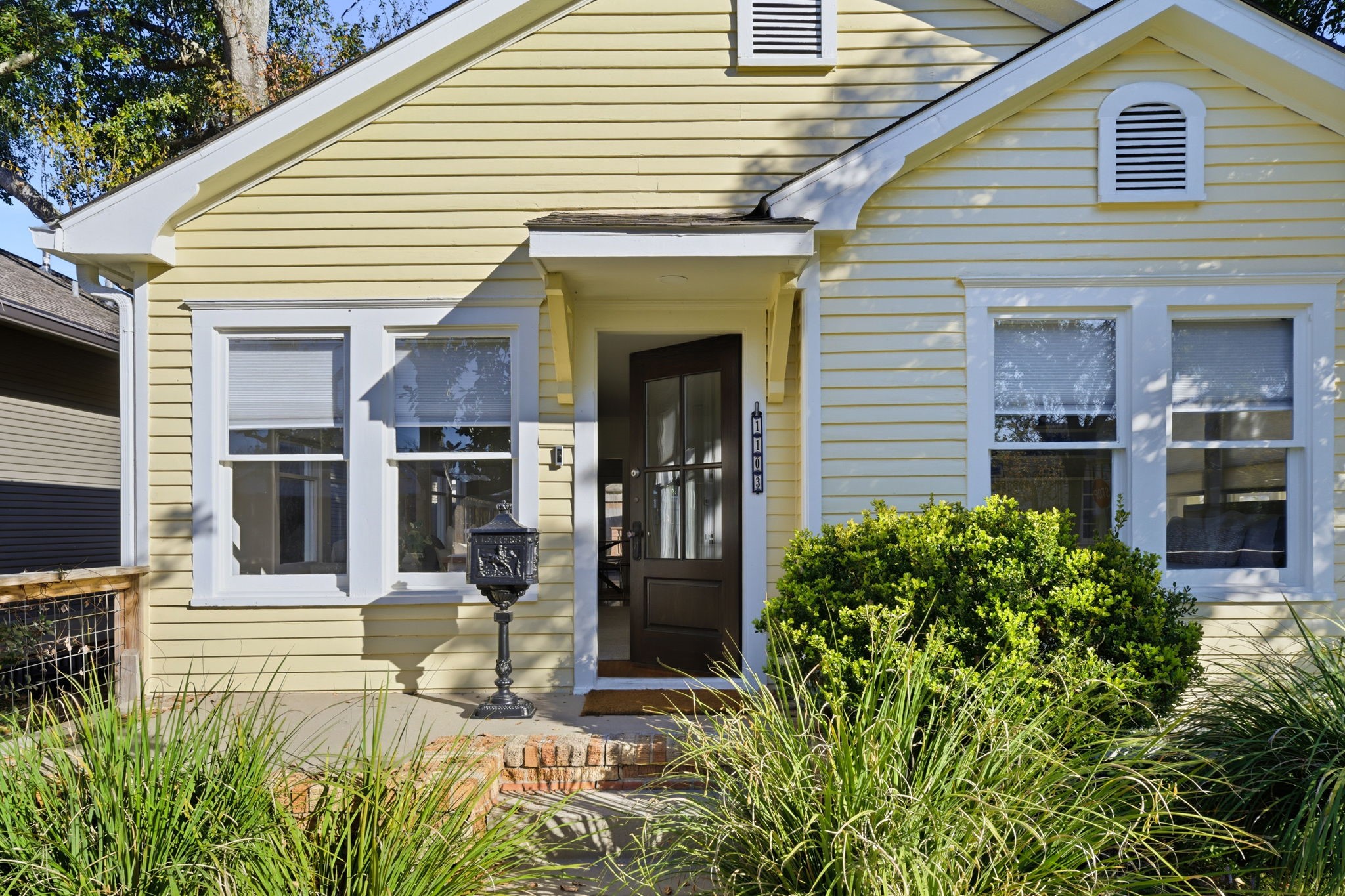 1103 Key Street Houston, TX 77009 - Photo 2 of 35 Charming yellow single-story home with a cozy front porch, surrounded by lush greenery.