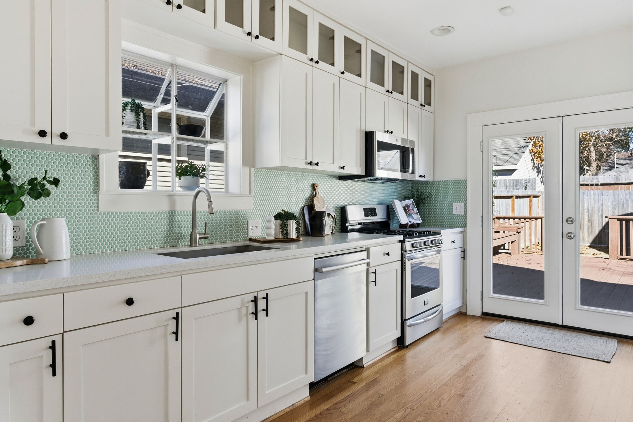 1103 Key Street Houston, TX 77009 - Photo 8 of 35 Bright, modern kitchen featuring white cabinetry, stainless steel appliances, and a fun tile backsplash.