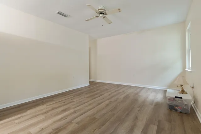 an empty room with wooden floor and fan