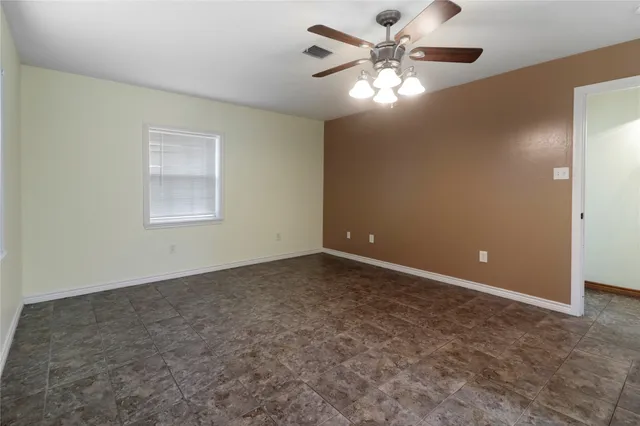 an empty room with a chandelier fan and windows