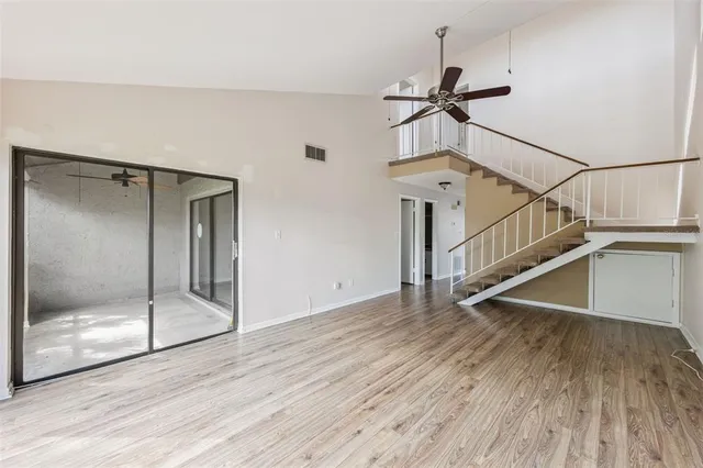 a view of a room with wooden floor staircase and a ceiling fan