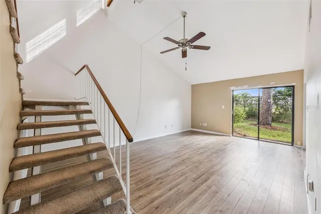 a view of an empty room with wooden floor and fan