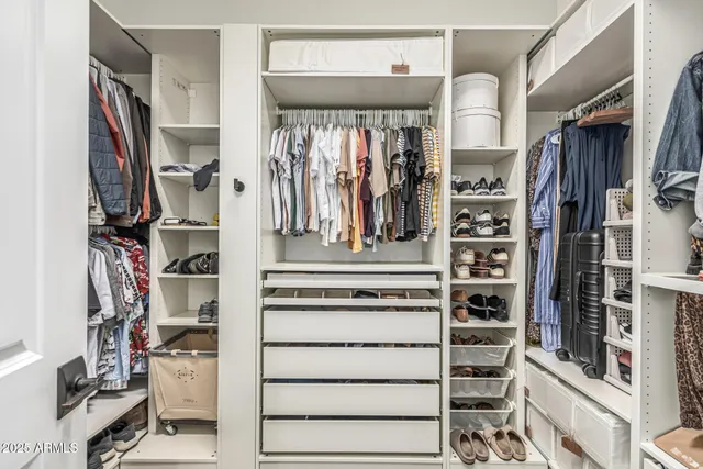a view of walk in closet with clothes and shoes