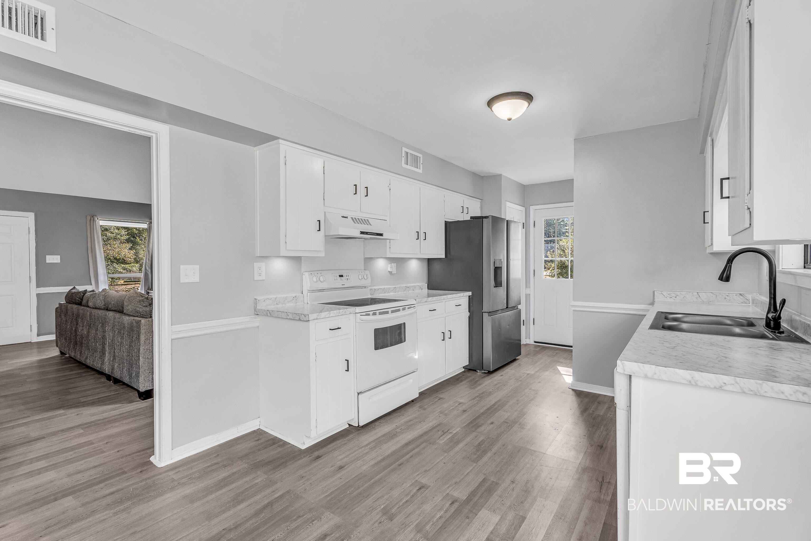 6135 Oak Cliff Drive Eight Mile, AL 36613 - Photo 12 of 30 Kitchen with white electric range oven, light countertops, white cabinetry, and light wood finished floors