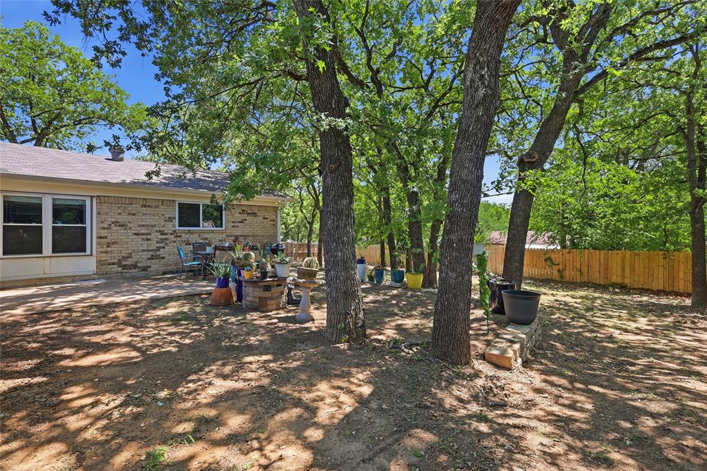 16 Coffee Tavern Road Bedford, TX 76022 - Photo 20 of 24 Expansive backyard featuring mature trees, a new wood fence, and a brick exterior with multiple windows
