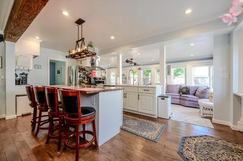 a view of a dining room and livingroom with furniture wooden floor a chandelier