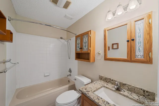 a bathroom with a granite countertop sink mirror toilet and bathtub