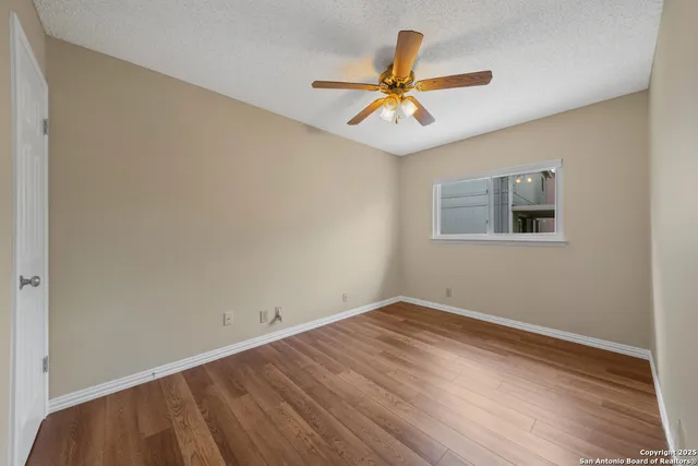 a view of a room with wooden floor and a ceiling fan