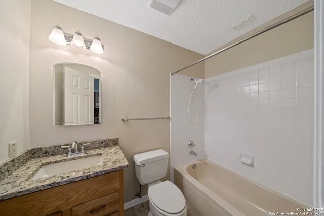 a bathroom with a granite countertop sink mirror vanity bathtub and a toilet
