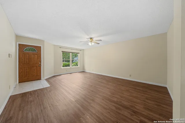a view of an empty room with wooden floor and a window