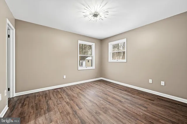 a view of an empty room with window and wooden floor
