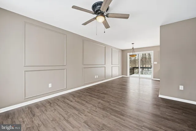 a view of empty room with wooden floor and ceiling fan