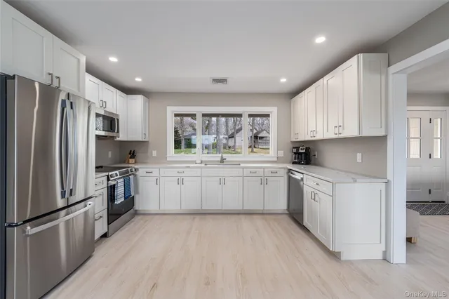 a kitchen with white cabinets stainless steel appliances and window