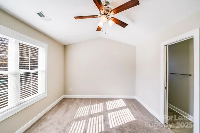 an empty room with a window and a ceiling fan