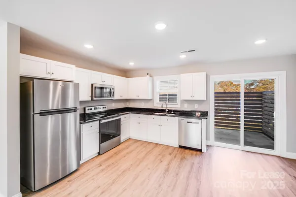 a kitchen with granite countertop a refrigerator and a stove top oven
