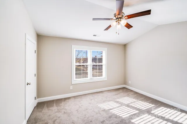 an empty room with windows and ceiling fan