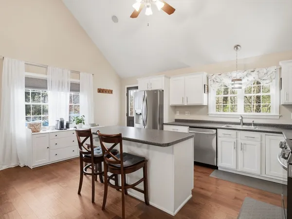a kitchen with stainless steel appliances granite countertop a stove a sink dishwasher a dining table and chairs with wooden floor
