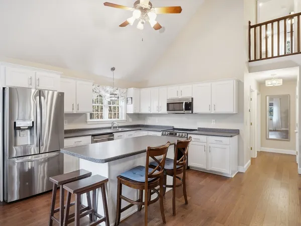 a kitchen with stainless steel appliances granite countertop a kitchen island hardwood floor and a sink