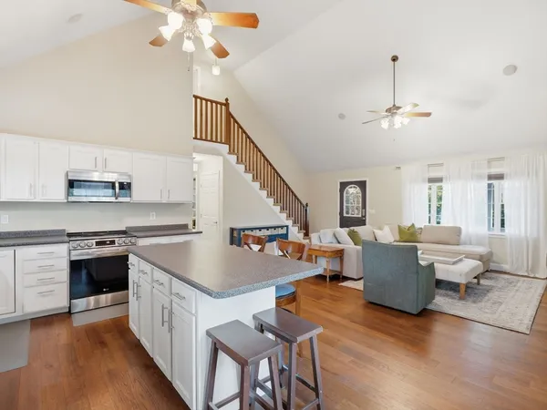 a kitchen with stainless steel appliances granite countertop a sink dishwasher a stove and a dining table with wooden floor