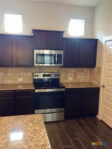 a kitchen with granite countertop wooden cabinets and stainless steel appliances