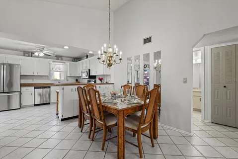 a dining room filled chandelier and kitchen view