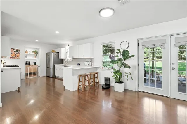 a view of kitchen with stainless steel appliances wooden floor and window