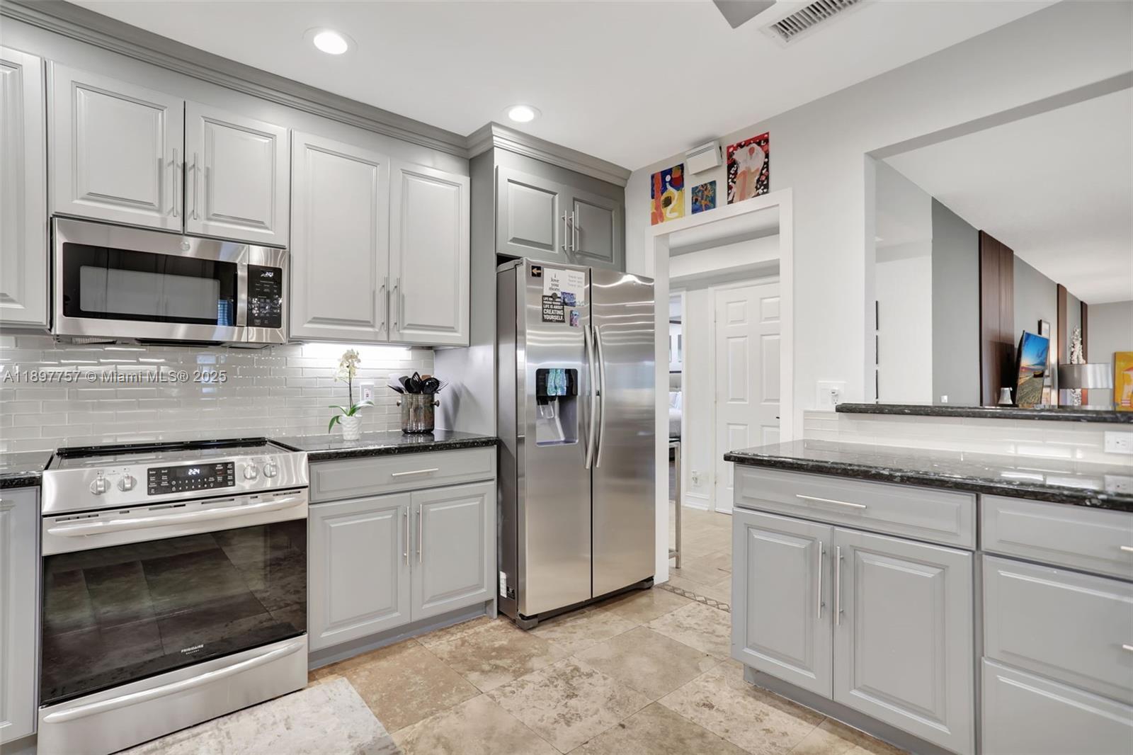 1128 West Cypress Drive, Unit V15 Pompano Beach, FL 33069 - Photo 11 of 41 a kitchen with stainless steel appliances granite countertop a stove a microwave and a refrigerator
