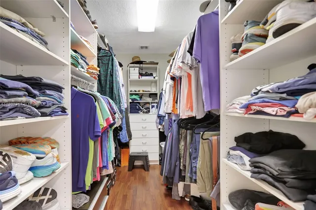 a view of walk in closet with clothes and shoes