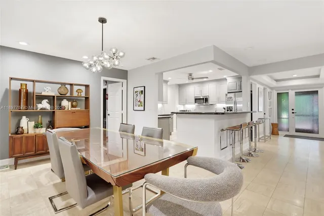 a dining room with wooden floor a chandelier a wooden table and chairs