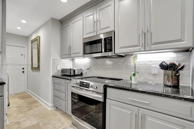 a kitchen with granite countertop white cabinets stainless steel appliances and sink