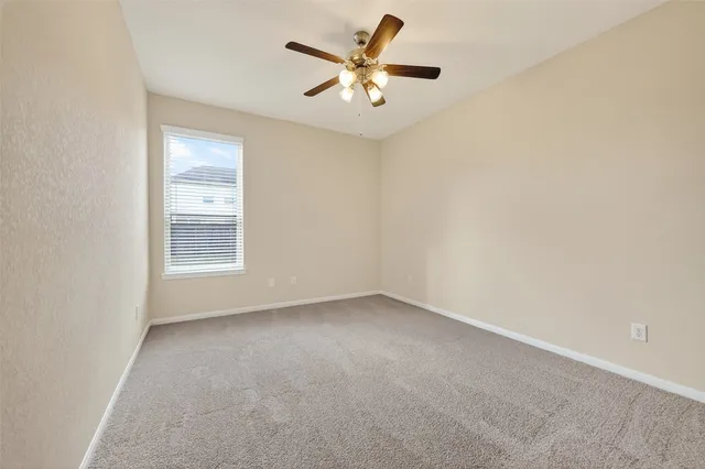 an empty room with a window and a ceiling fan