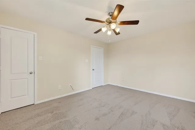an empty room with a chandelier fan and a ceiling fan