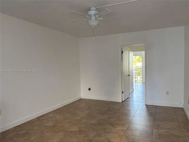 an empty room with an entryway and chandelier fan