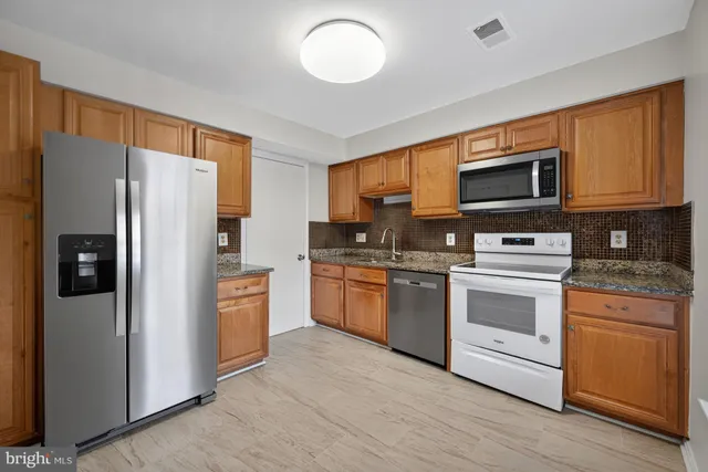 a kitchen with stainless steel appliances granite countertop a refrigerator stove microwave and sink