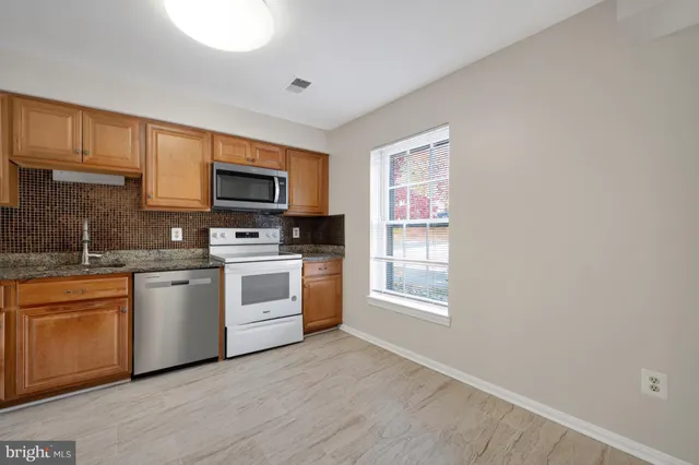 a kitchen with stainless steel appliances granite countertop a stove top oven a sink dishwasher and a microwave oven with cabinets