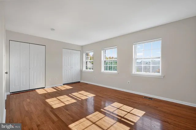 a view of an empty room with window and wooden floor