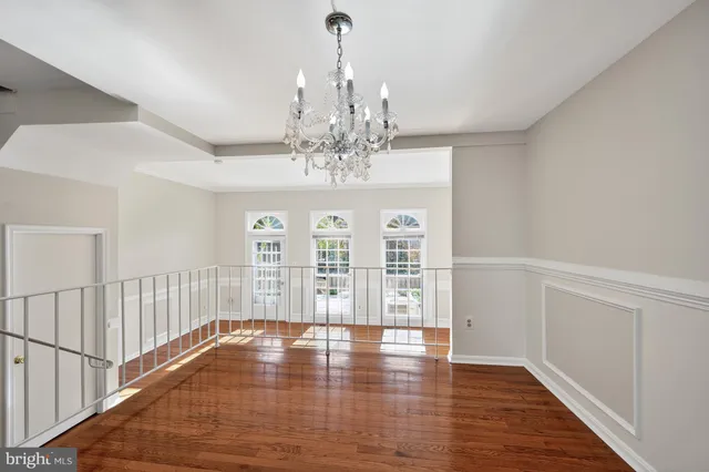 a view of an empty room with wooden floor and fan