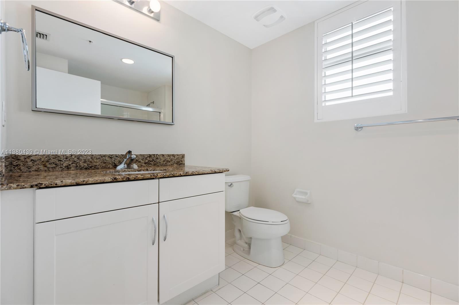 7290 Southwest 90th Street, Unit F606 Miami, FL 33156 - Photo 6 of 17 a bathroom with a granite countertop toilet a sink and a mirror