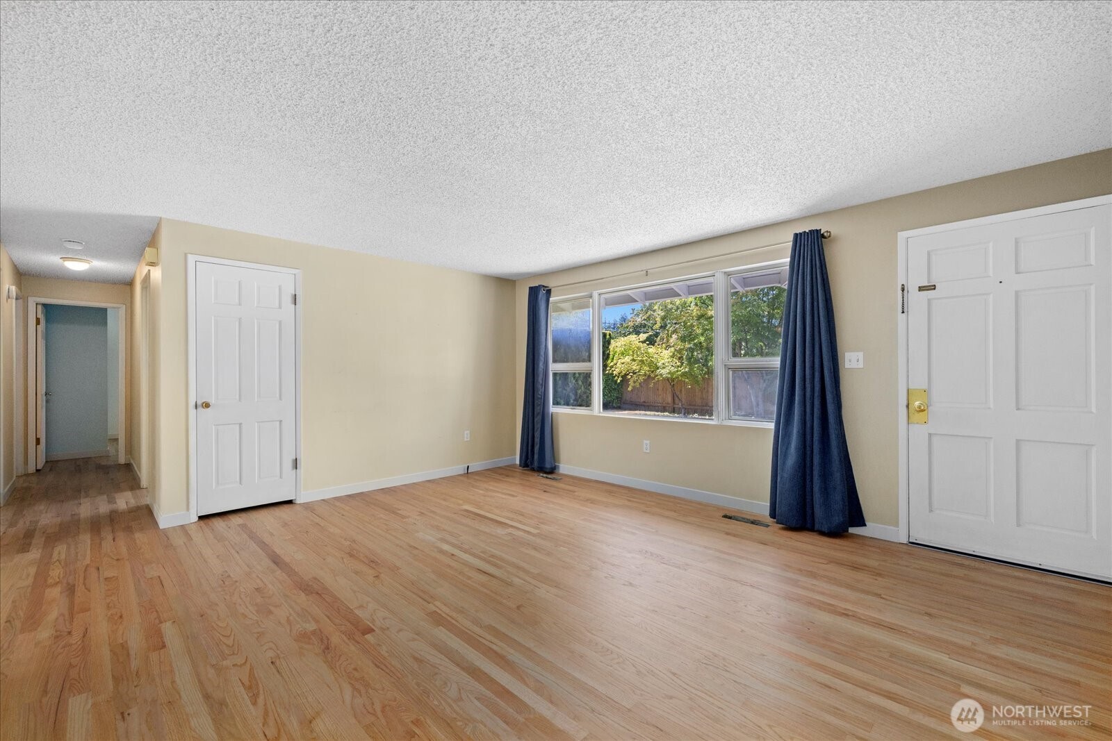 9125 Meadow Way Everett, WA 98208 - Photo 7 of 27 a view of an empty room with wooden floor and a window