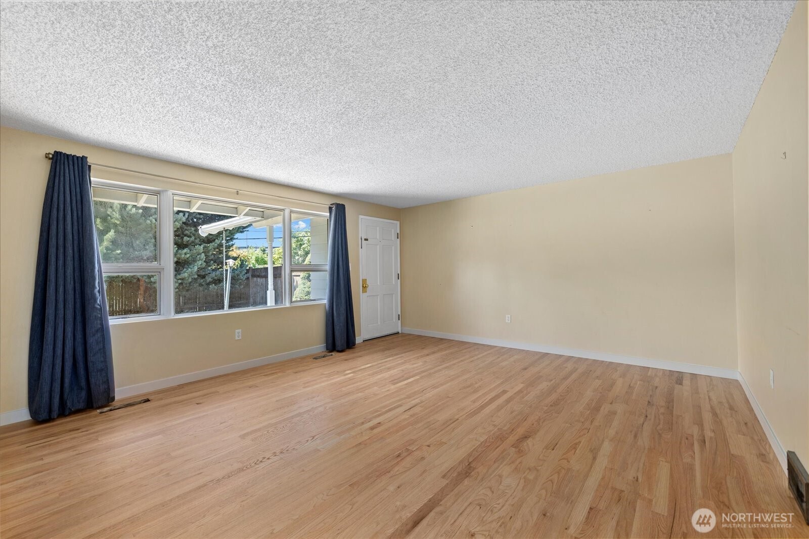 9125 Meadow Way Everett, WA 98208 - Photo 8 of 27 an empty room with wooden floor and windows