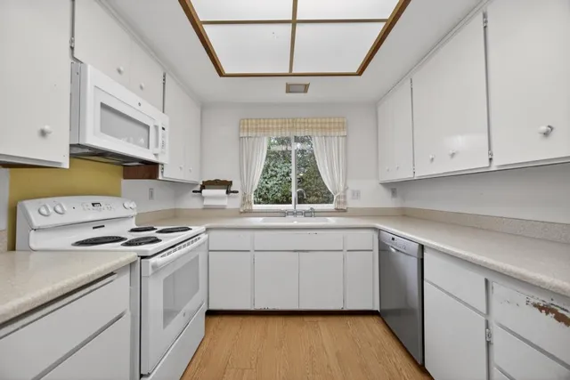 a kitchen with stainless steel appliances white cabinets a sink and a stove