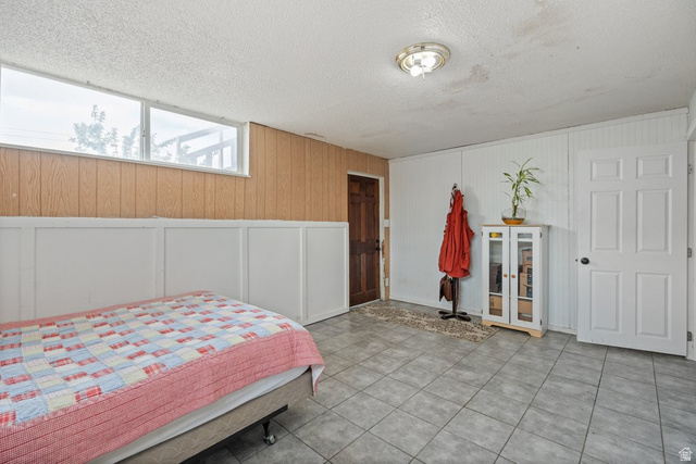 149 West 1600th Street South Mapleton, UT 84664 - Photo 18 of 44 Bedroom featuring a decorative wall, wooden walls, a textured ceiling, and light tile patterned flooring