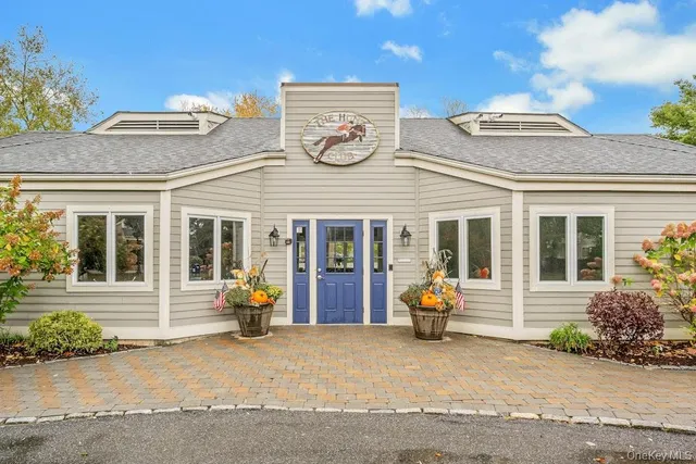 front view of a brick house with potted plants and a bench