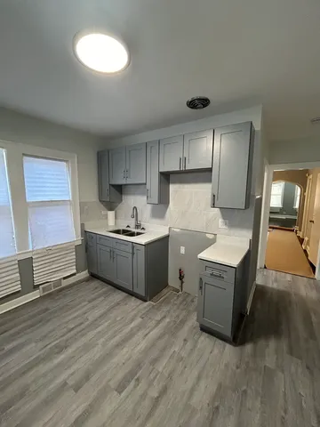 a living room with stainless steel appliances kitchen island granite countertop a sink a counter space and cabinets