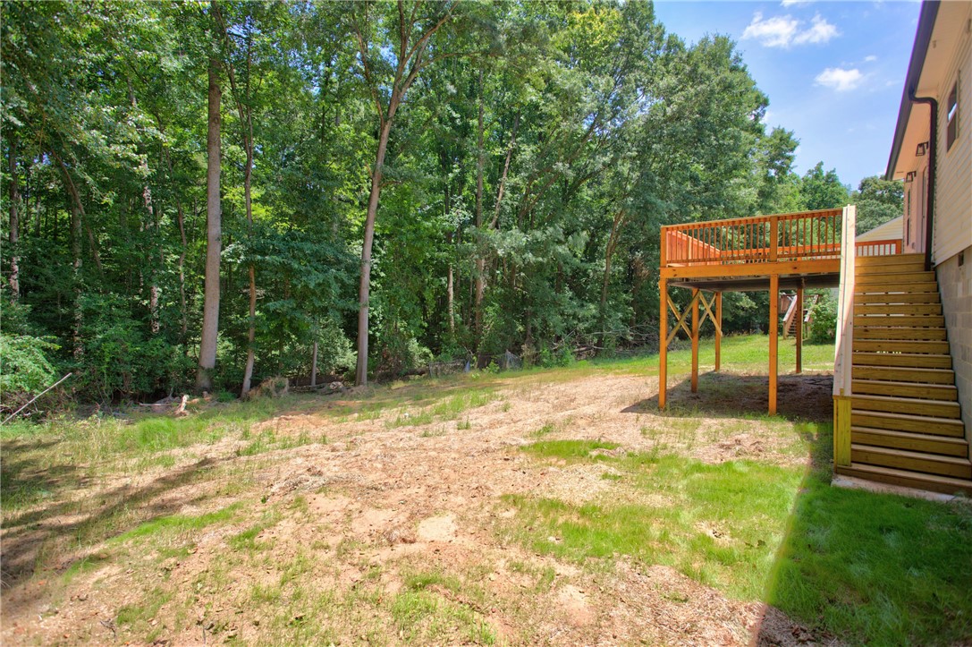 223 Maple Drive Anderson, SC 29621 - Photo 40 of 45 An elevated wooden deck with stairs provides outdoor living space, overlooking a natural, treed yard.
