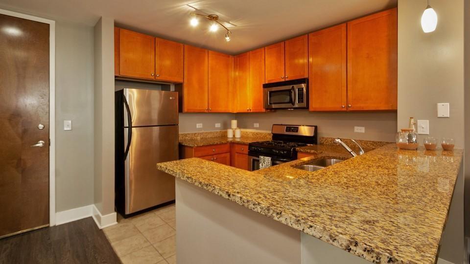 a kitchen with granite countertop a refrigerator a sink a stove a microwave a counter top and cabinets
