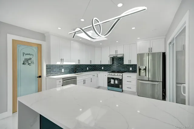 a kitchen with granite countertop a sink stainless steel appliances and white cabinets